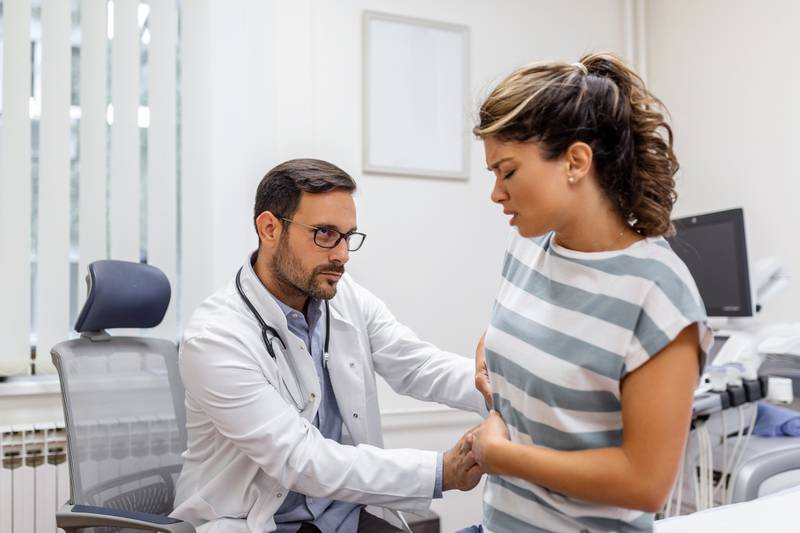 Mulher com dor próxima aos rins sendo consultada por um médico