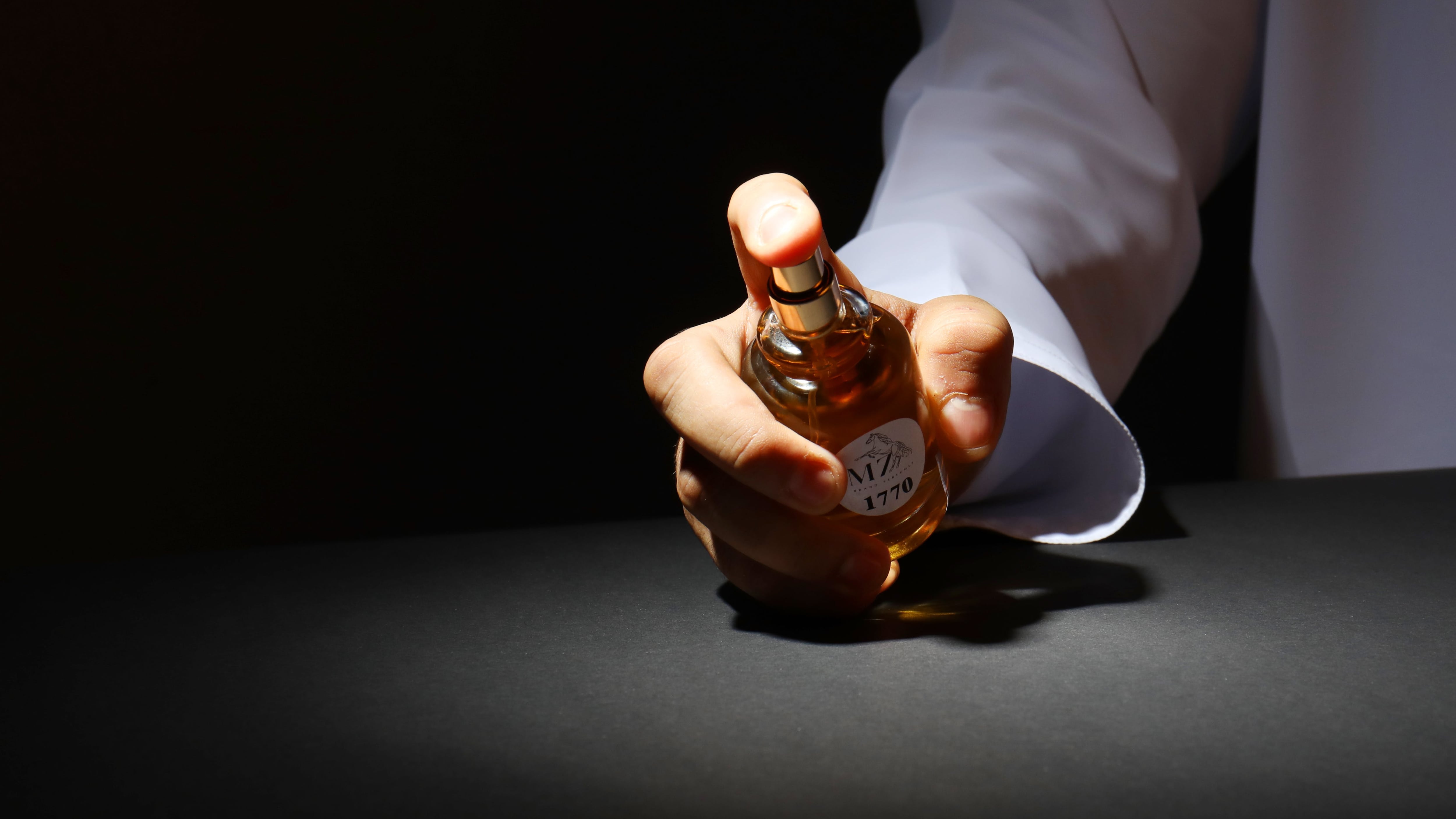 Mão borrifando frasco de perfume