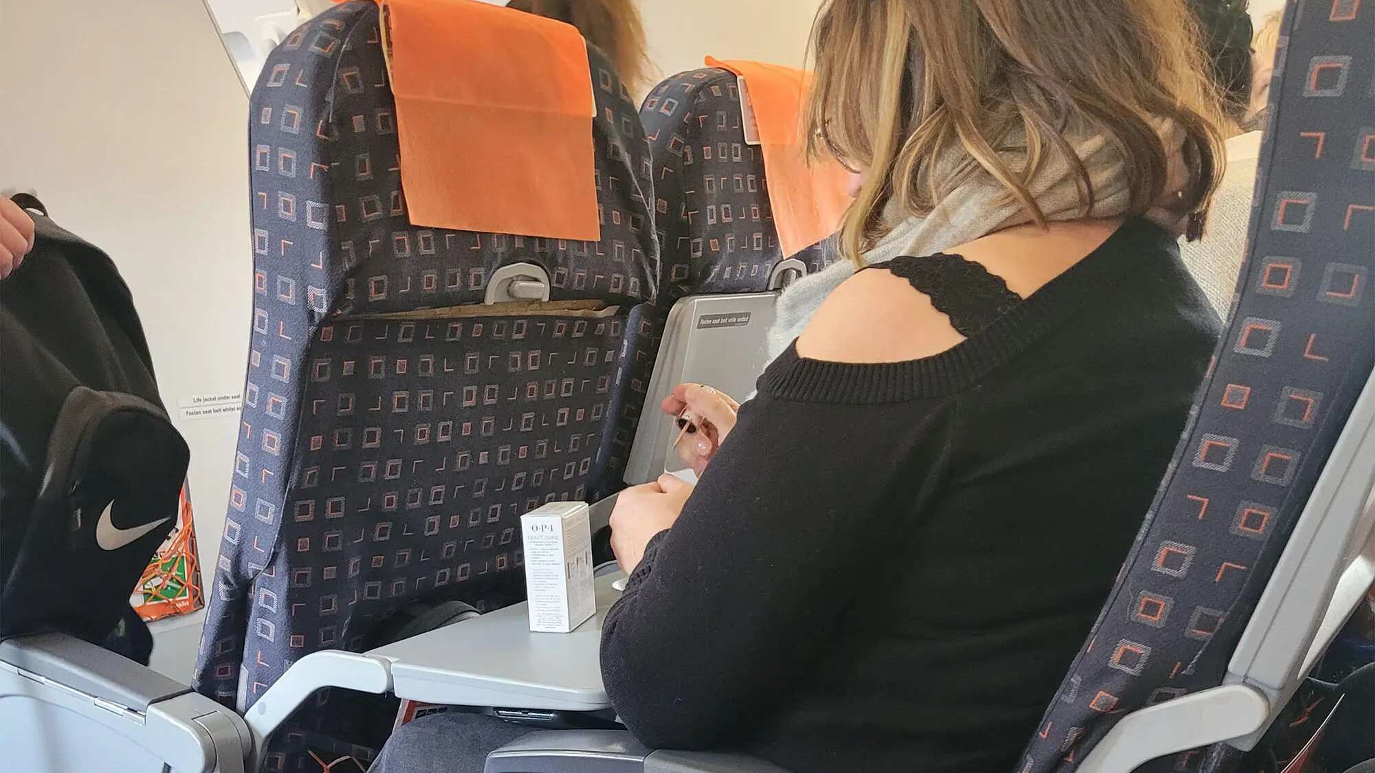 Mujer no presta atención a azafata y se pinta las uñas como si nada pasara.