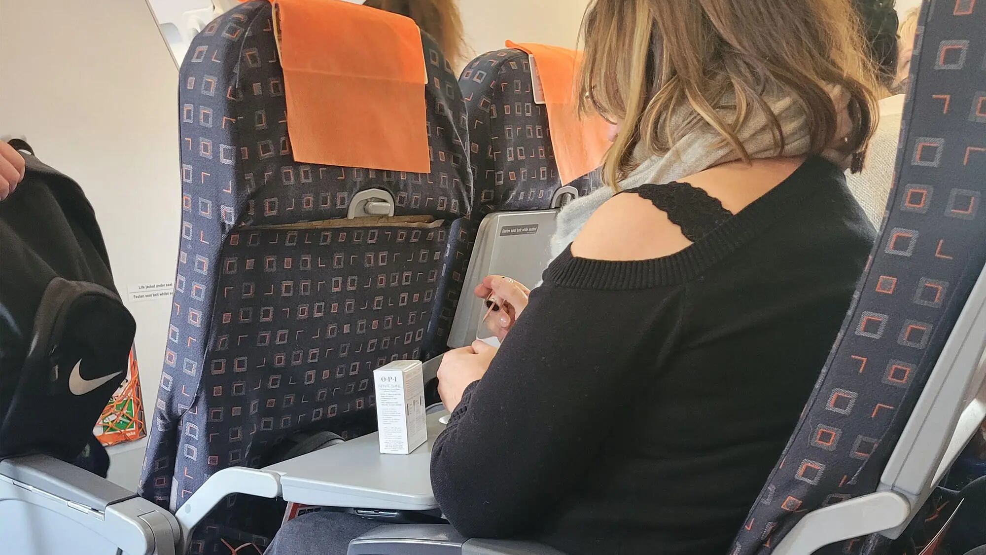 Mujer no presta atención a azafata y se pinta las uñas como si nada pasara.