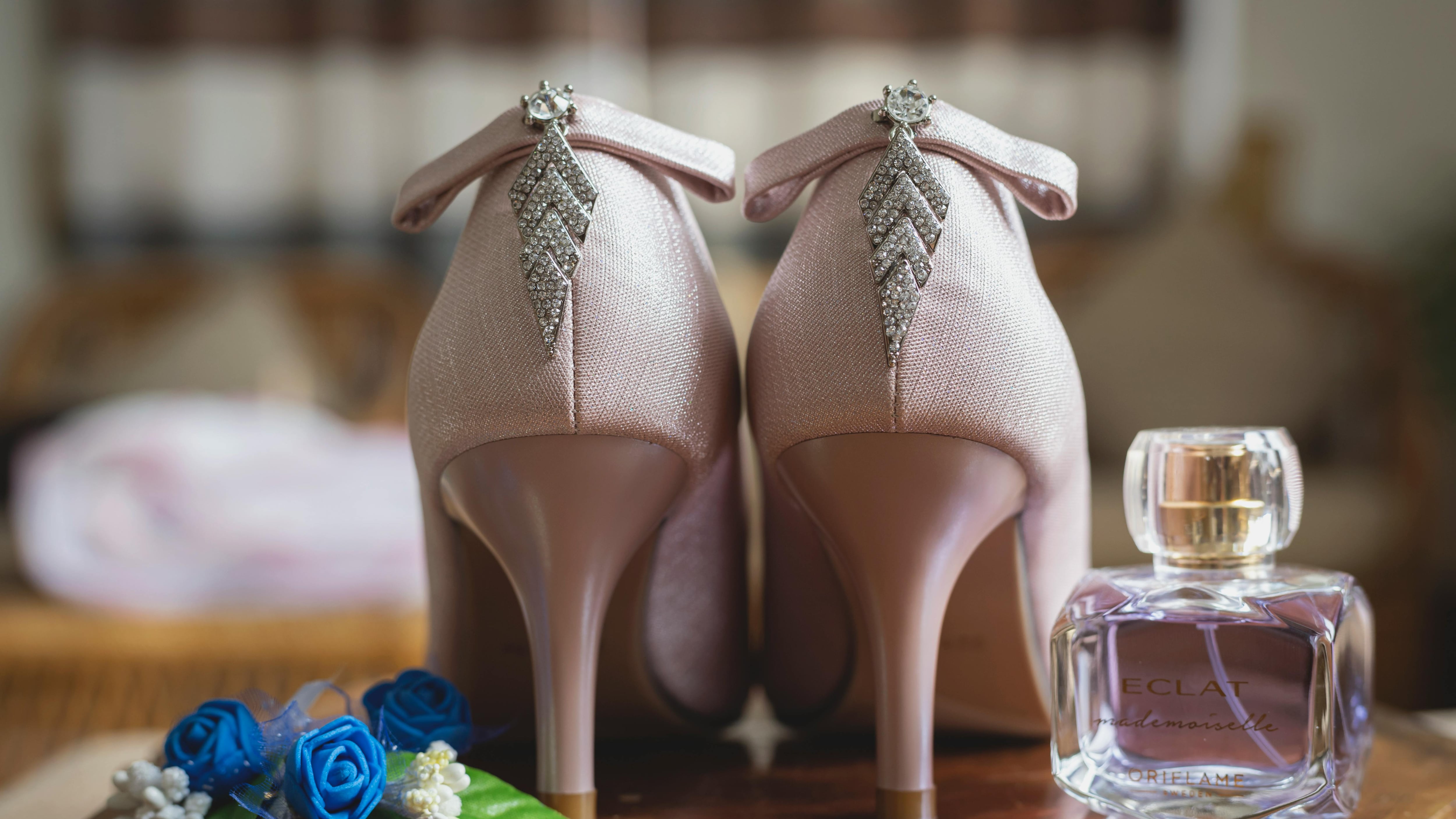 Frasco de perfume ao lado de salto agulha rosa