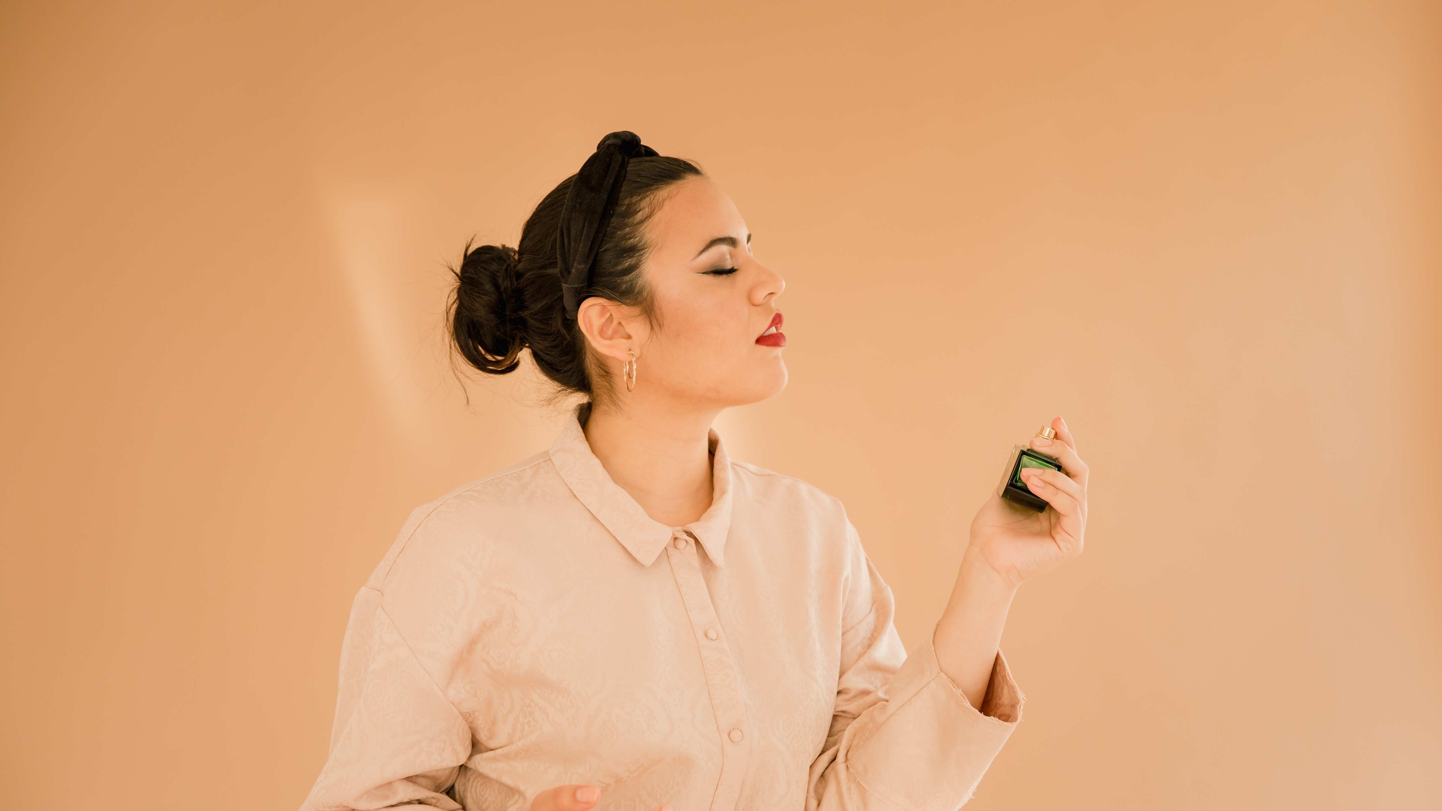 Mulher borrifando frasco de perfume