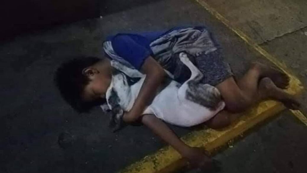 Niño sin hogar se aferra a su perrito para luchar contra el frío de la noche.