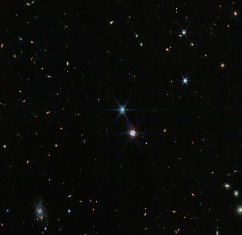 El sistema de Neptuno está acompañado de varias galaxias de fondo.