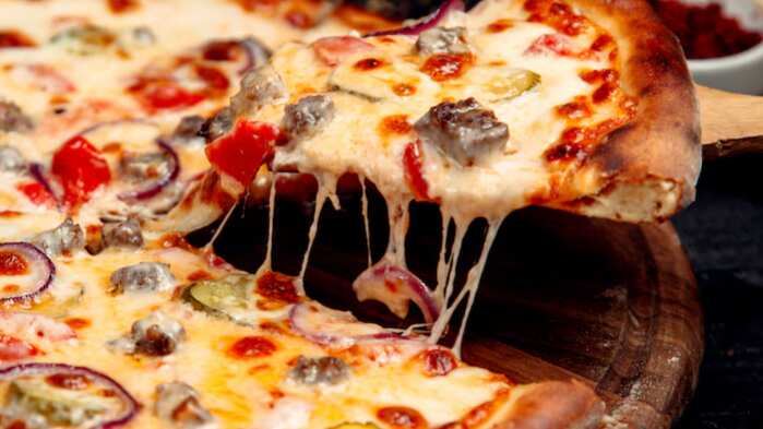 Una rebanada de pizza crujiente con carne y queso.