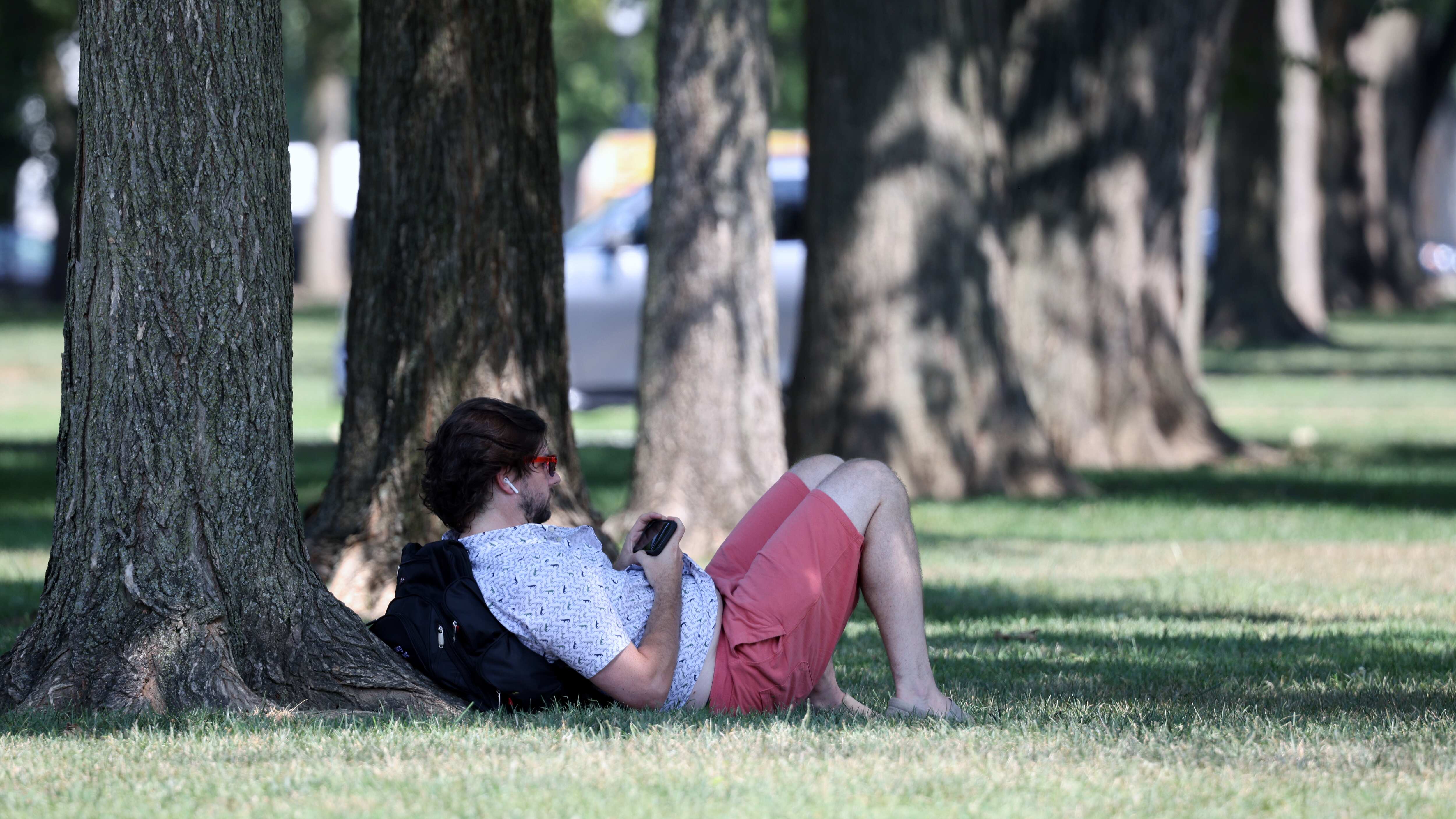 WASHINGTON, DC - 12 DE AGOSTO: Una persona se relaja a la sombra de un árbol en el National Mall mientras las temperaturas alcanzan los 97 grados fahrenheit el 12 de agosto de 2021 en Washington, DC. Un informe sobre el clima publicado recientemente por las Naciones Unidas predice que el mundo seguirá calentándose y que las olas de calor, las inundaciones y los incendios devastadores serán cada vez más frecuentes.