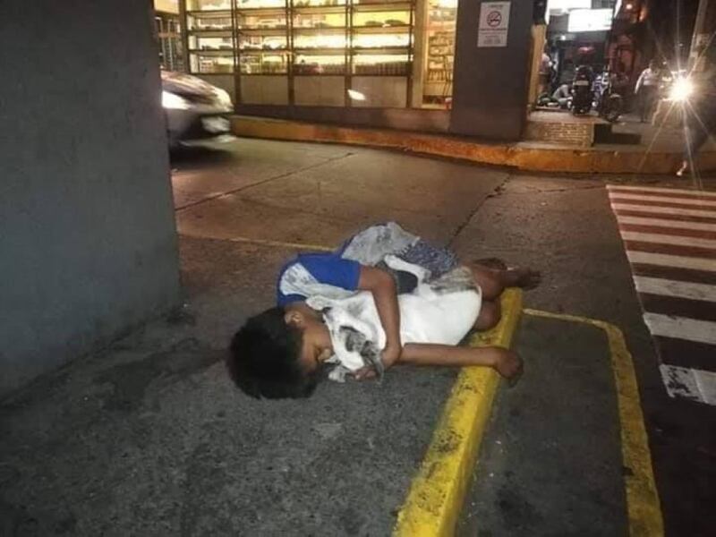 Niño sin hogar se aferra a su perrito para luchar contra el frío de la noche.