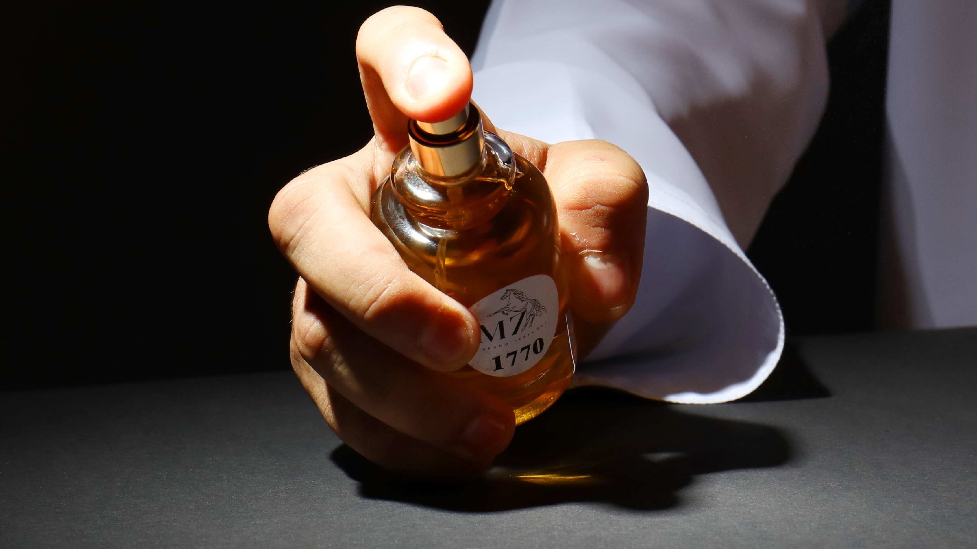 Braço masculino segurando perfume