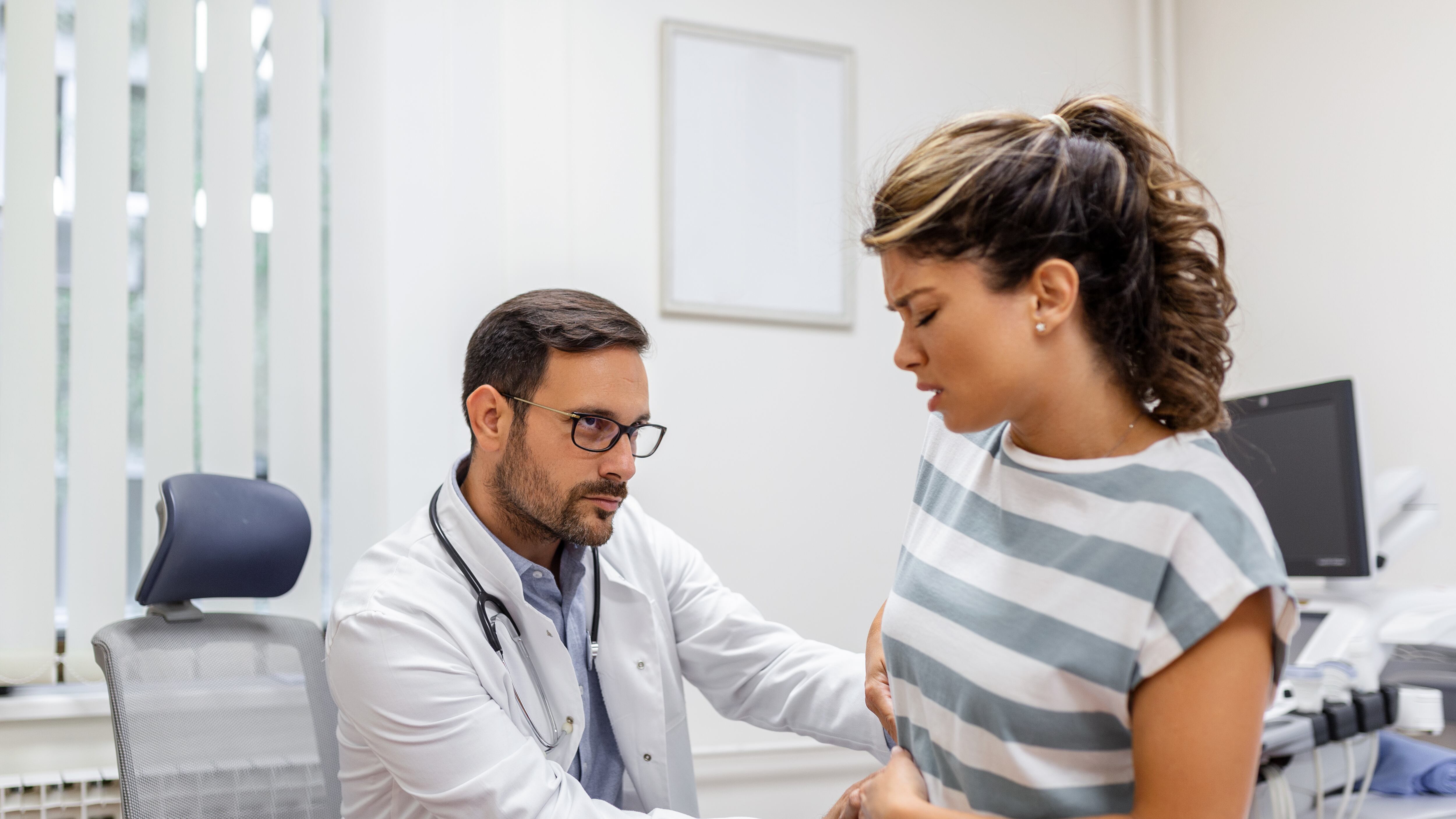 Mulher com dor próxima aos rins sendo consultada por um médico